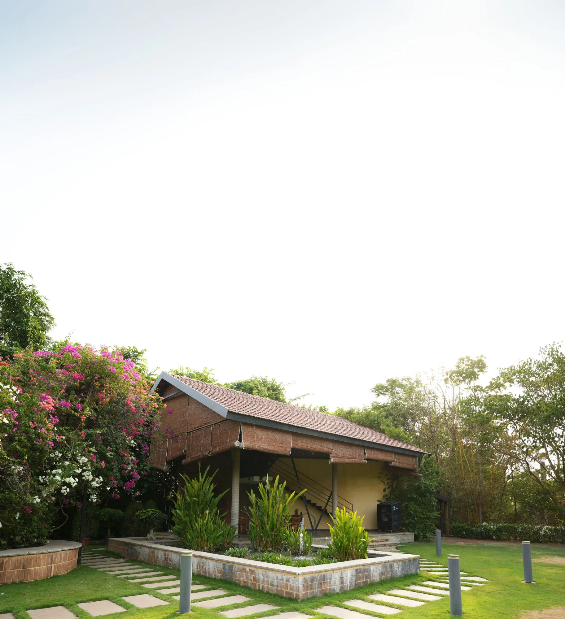 Covered lounge pavilion with seating beside the planted courtyard at Woods Shamshabad